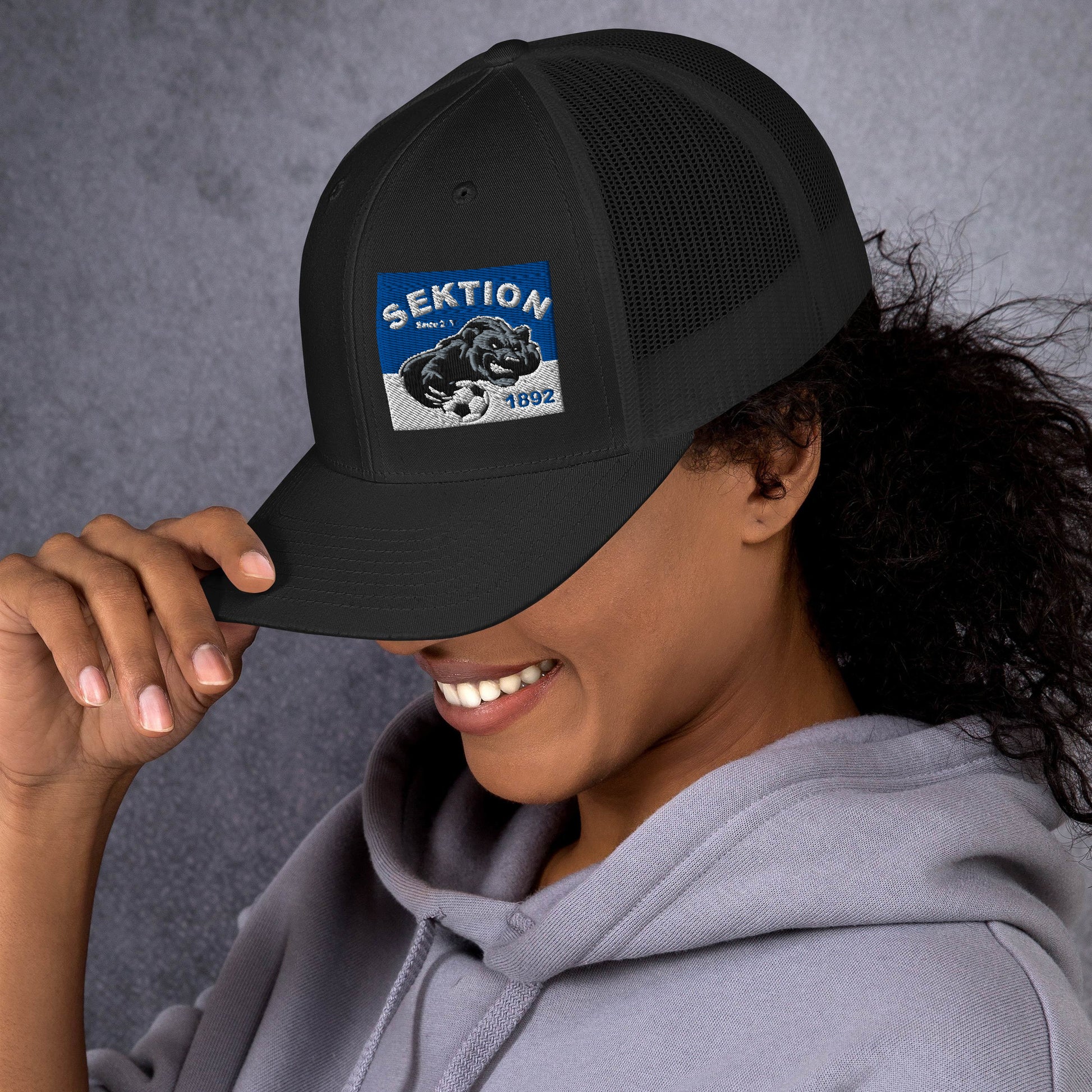 Retro schwarze Trucker-Cap von Sportswear Iron Monkey 23, seitlich sichtbar, mit Mesh-Design und klassischen Trucker-Details.